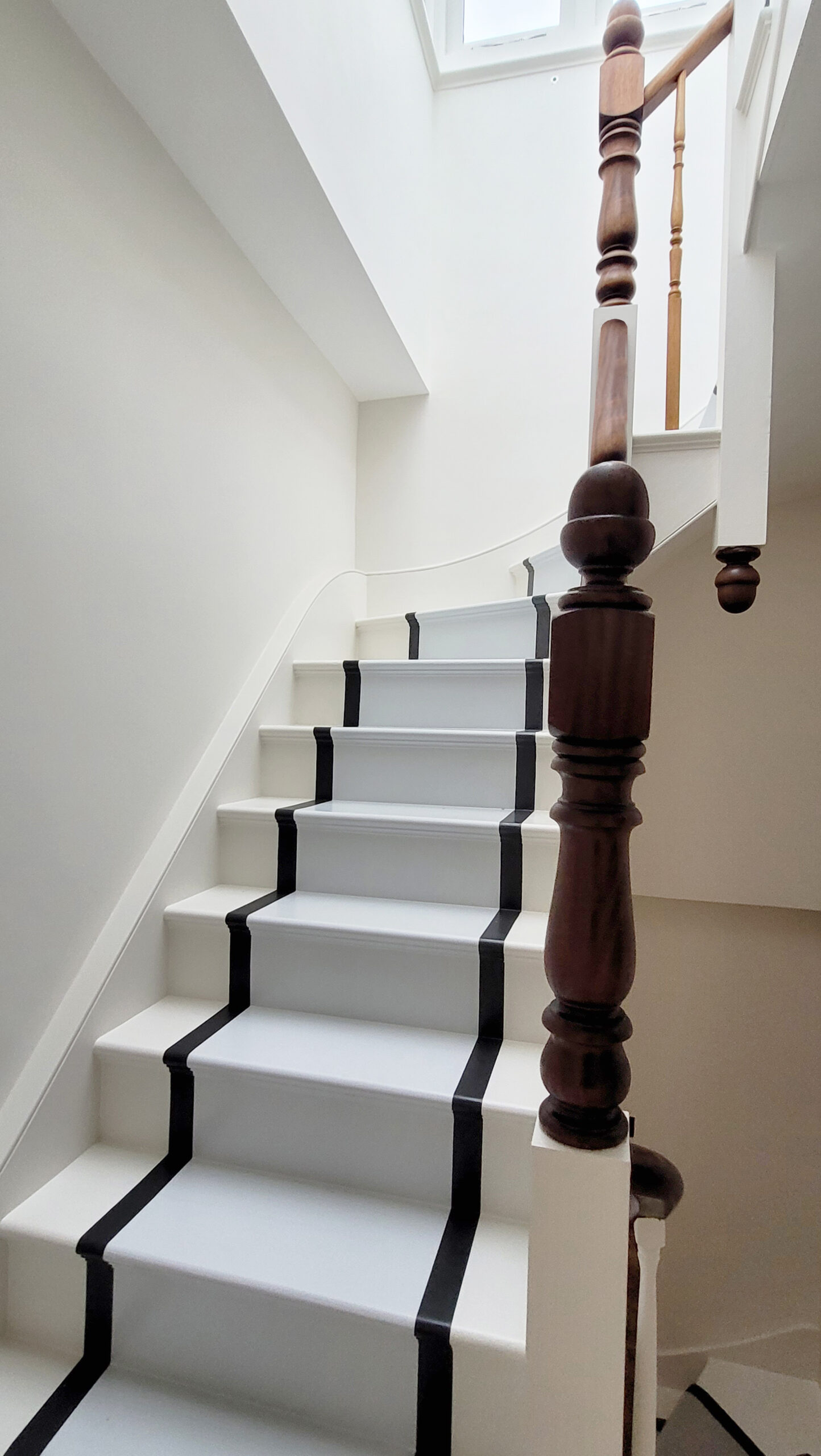 White staircase with dark handrail and stripes.